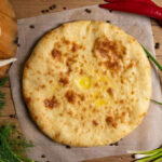 Круглый осетинский пирог с сыром на деревянной доске — рецепт от Eatery5
