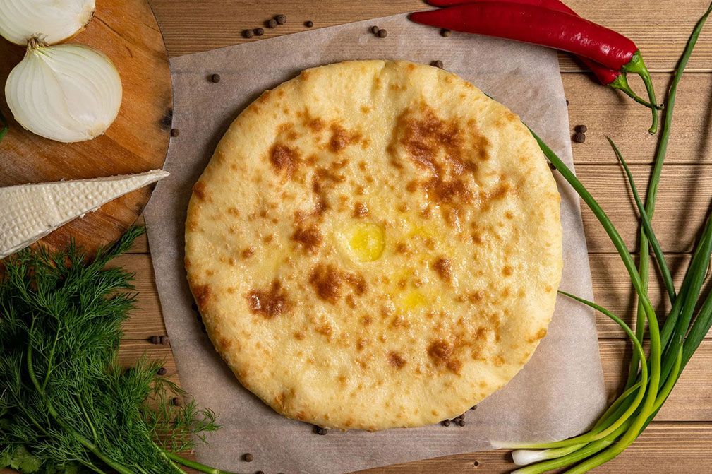 Круглый осетинский пирог с сыром на деревянной доске — рецепт от Eatery5